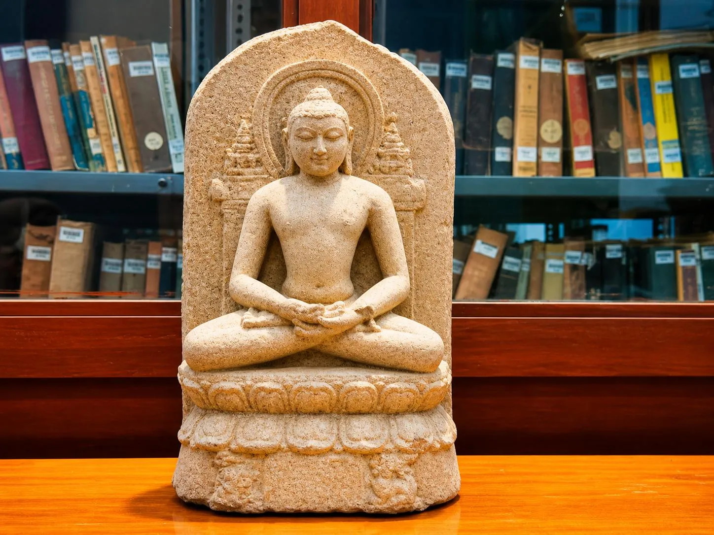 Carved stone sculpture of a seated figure in meditation, displayed in the university museum
